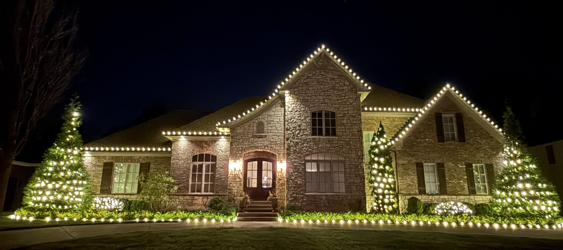 stone house lit with warm white Christmas lights Louisville KY