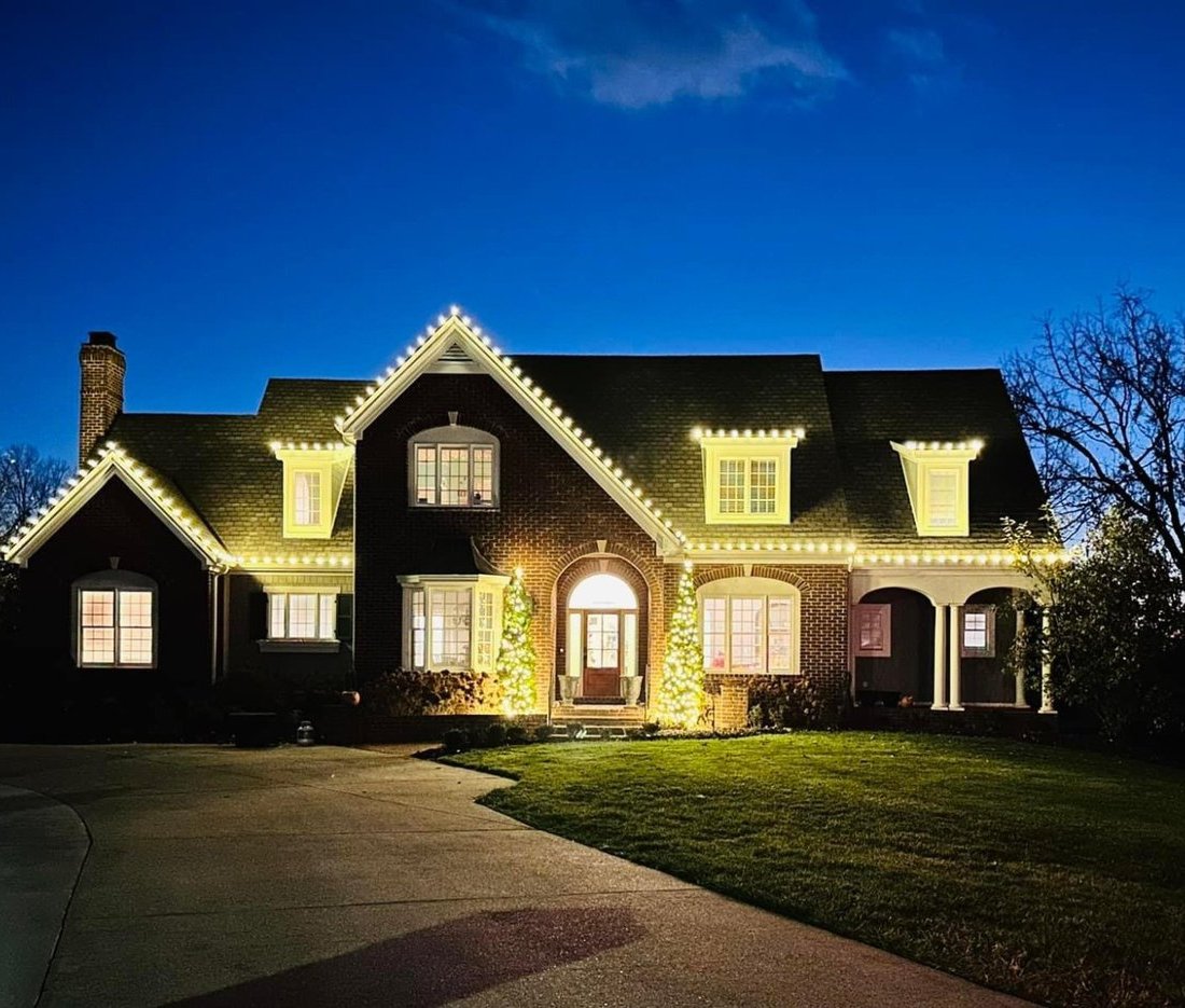 luxury home with warm white Christmas lights at dusk Louisville KY