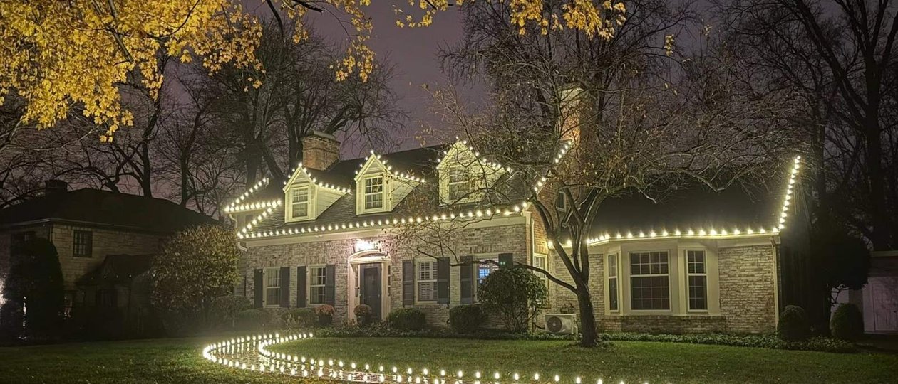 warm white Christmas lights on a stone cottage with a lit pathway Louisville KY